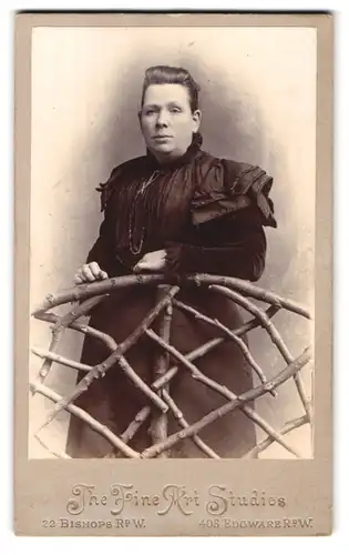 Fotografie F. W. Wood, London, 22 Bishop Road W., breitere Dame an Holzzaun lehnend