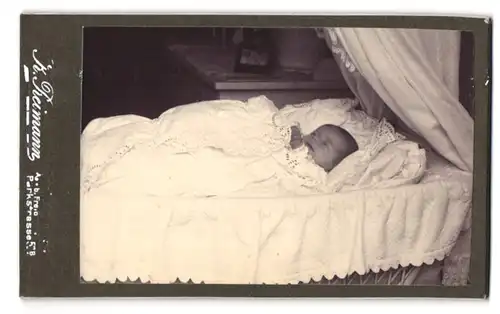 Fotografie K. Reimann, Friedeburg, Parkstrasse 53 B, Portrait niedliches Baby in der Wiege liegend