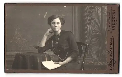 Fotografie Aug. Jensen, Quern-Dingholz, Portrait bürgerliche Dame mit Buch am Tisch sitzend