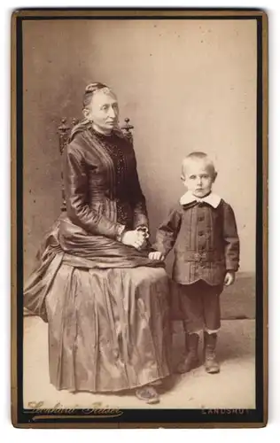 Fotografie Leonhard Reiser, Landshut, Maximilianstr. 1, betagte Dame im Kleid & frecher blonder Bube im Anzug