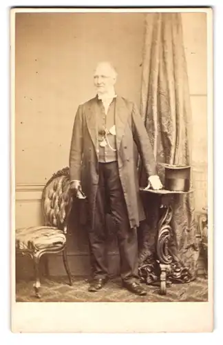 Fotografie the Lonodn Stereoscopic & Photographic Company, London, Cheapside, Portrait älterer Herr im Mantel mit Fliege