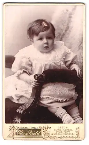 Fotografie Allen Nield, Leeds, Queens Arcade, Portrait niedliches Kleinkind im hübschen Kleid auf Stuhl sitzend
