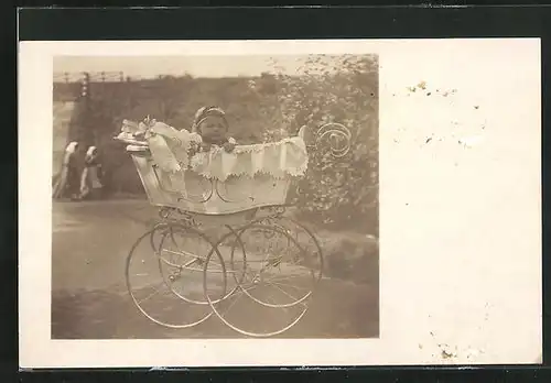 Foto-AK Baby im Kinderwagen, Im Hintergrund Frauen