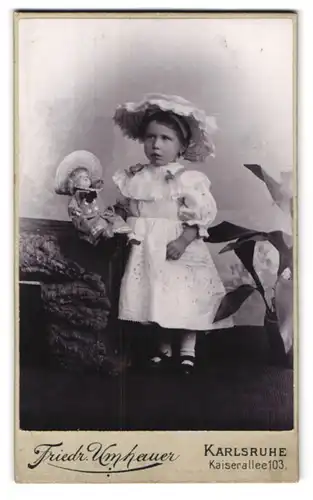 Fotografie Friedr. Umhauer, Karlsruhe, Kaiserallee 103, Portrait Mädchen im weissen Kleid mit Hut und Puppe