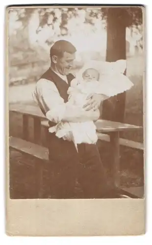 Fotografie Schnappschuss Vater mit Baby im Arm im Garten