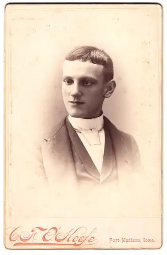 Fotografie C.F. O`Keefe, Fort Madison / Iowa, Portrait schielender Bursche im Anzug mit weisser Krawatte