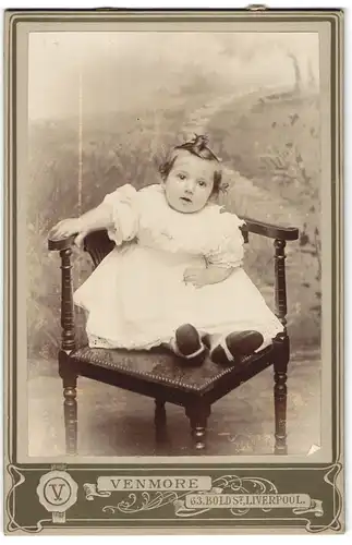 Fotografie Venmore, Liverpool, 63, Bold St., Portrait niedliches Kleinkind im weissen Kleid auf Stuhl sitzend