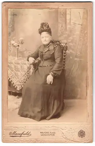 Fotografie Mansfield, Leicester, Welford Place, Ältere Dame mit geschmückter Haube sitzt auf Stuhl