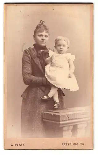 Fotografie C. Ruf, Freiburg i. B., Kaiserstr. 5, Portrait stolze junge Mutter mit niedlicher Tochter auf dem Arm