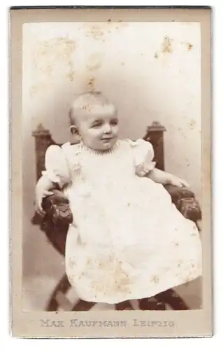 Fotografie Max Kaufmann, Leipzig, Marienstr., Portrait lächelndes Kleinkind im weissen Kleidchen