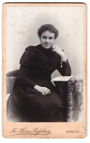 Fotografie Fr. Herm. Rossberg, Sebnitz i/S., Böhmische Strasse 318 Q., Portrait lächelnde Frau im schwarzem Kleid