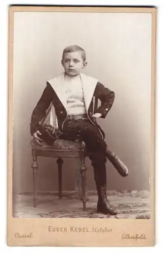 Fotografie Eugen Kegel, Cassel, Gr. Rosenstr. 5, Portrait frecher Bube im Anzug und Schürstiefeln