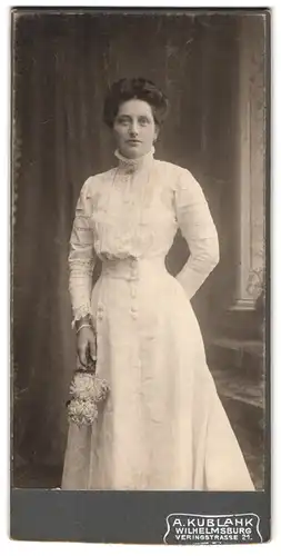 Fotografie A. Kublank, Wilhelmsburg, Veringstr., 21, Dame trägt weisses hochgeschlossenes Kleid und hält Blumenstrauss