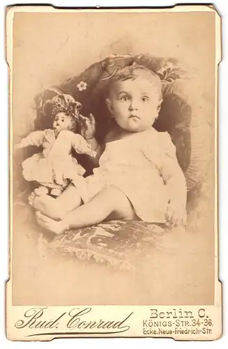 Fotografie Rud. Conrad, Berlin, Königsstrasse 34-36, niedliches Baby mit Puppe