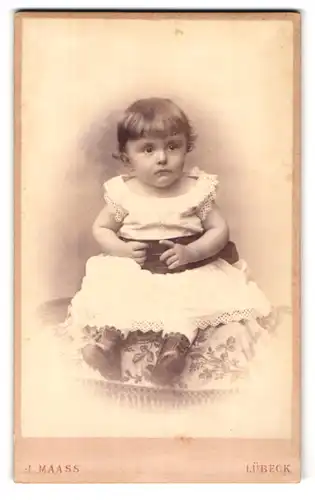Fotografie J. Maass, Lübeck, Breitestrasse 37, Portrait niedliches Kleinkind im weissen Kleid