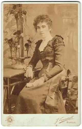 Fotografie J. Kennerell, Wisbech, Portrait junge Dame im Kleid am Tisch sitzend
