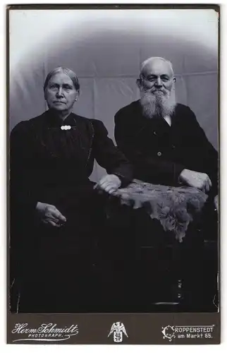 Fotografie Herm. Schmidt, Croppenstedt, Am Markt 65, Portrait älteres Paar in hübscher Kleidung am Tisch