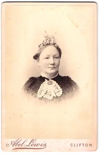 Fotografie Abel Lewis, Clifton, Portrait hübsche Dame mit Rüschenkopfschmuck und Brosche am Blusenkragen