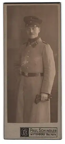 Fotografie Paul Schindler, Wittenberg, Portrait Soldat in Felgrau Uniform-Mantel mit Mütze
