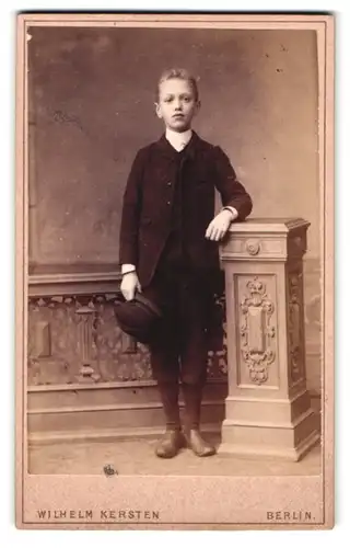 Fotografie Wilhelm Kersten, Berlin, Krausenstr. 40, Portrait frecher blonder Bube an einem Geländer stehend