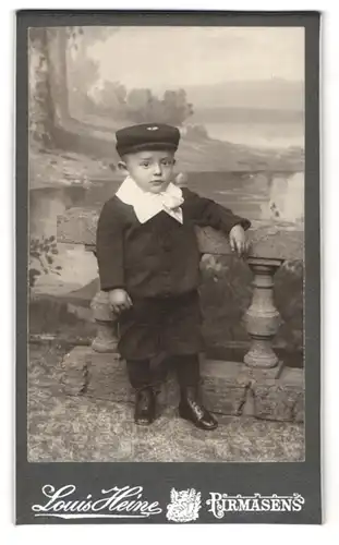 Fotografie Louis Heine, Pirmasens, Portrait niedlicher Bube mit Mütze im Anzug