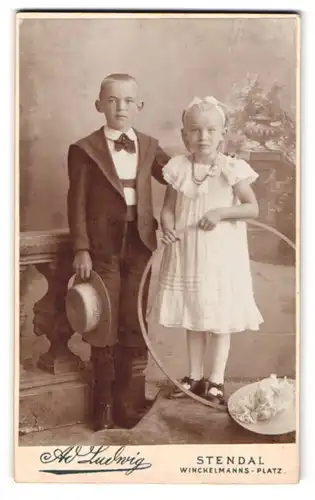 Fotografie Ad. Ludwig, Stendal, Winckelmanns-Platz, Portrait niedliches Kinderpaar mit Reifen in hübscher Kleidung