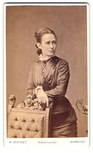 Fotografie W. Höffert, Hamburg, Jungfernstieg 6, Portrait bildschöne Frau im eleganten Kleid am Stuhl stehend