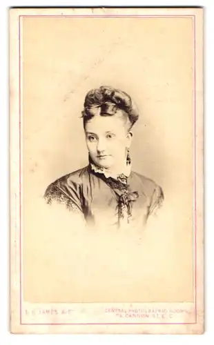 Fotografie D. B. James, London, 76 Cannon St., Portrait bildschöne junge Frau mit Ohrringen und Brosche am Kragen