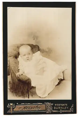 Fotografie Hartley, Burnley, Westgate, Portrait niedliches Kleinkind im weissen Kleid auf Sessel sitzend