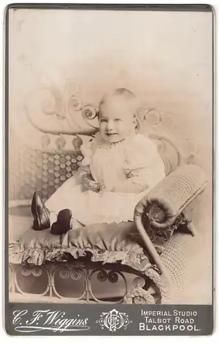Fotografie C. F. Wiggins, Blackpool, Talbot Road, Portrait kleines Mädchen im weissen Kleid auf Sofa sitzend