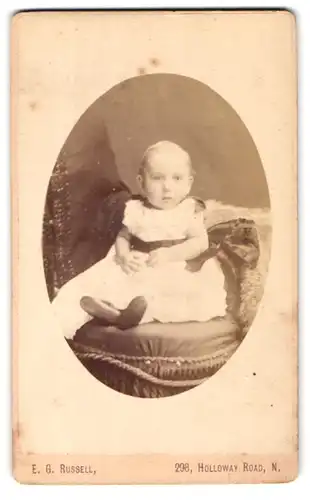 Fotografie E. G. Russel, London, 298 Holloway Road, Portrait niedliches Kleinkind im weissen Kleid