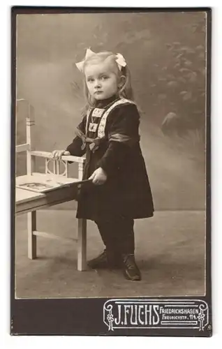 Fotografie J. Fuchs, Friedrichshagen, Friedrichstrasse 114, Portrait kleines Mädchen im Kleid mit einem Bilderbuch