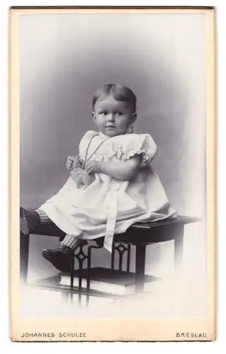 Fotografie Johannes Schulze, Breslau, Matthiasplatz 13, Portrait niedliches Kleinkind im weissen Kleid mit Spieltier