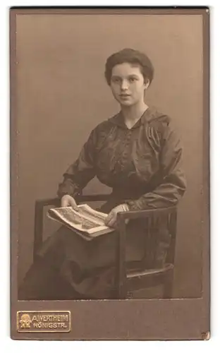 Fotografie A. Wertheim, Berlin, Königstrasse, Portrait junge Dame in hübscher Bluse mit Zeitung auf Stuhl sitzend