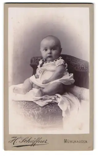 Fotografie H. Schäffner, Mühlhausen i / Thür., Portrait niedliches Baby im weissen Hemd mit nackigen Füssen