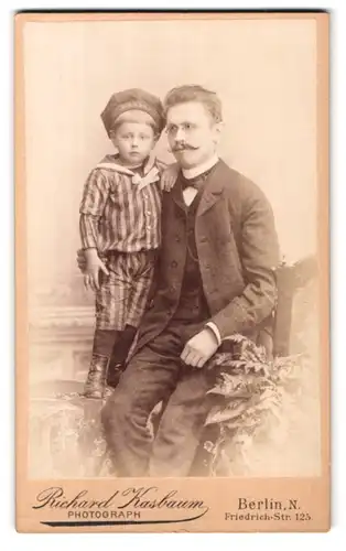 Fotografie Richard Kasbaum, Berlin, Friedrichstr. 125, Portrait stolzer Vater im Anzug mit niedlichem Buben im Arm