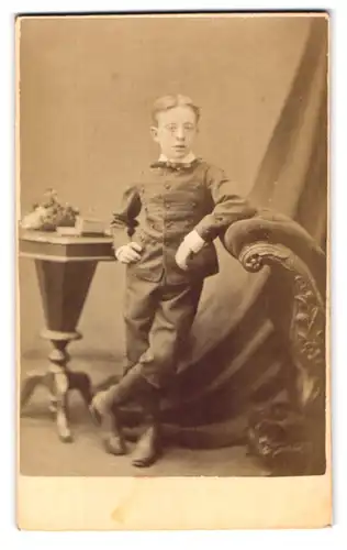 Fotografie F. W. Evans, London-SE, 246, Old Kent Road, Portrait kleiner Junge im Anzug an Sessel gelehnt