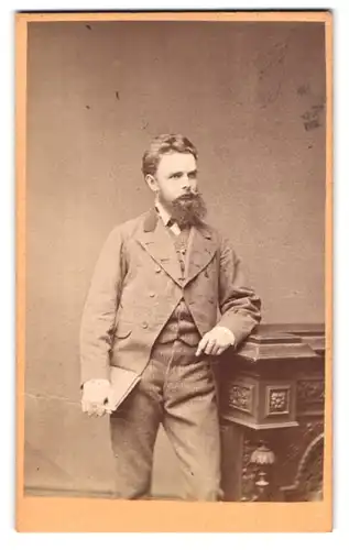 Fotografie Joh. Hassel, Prag, Ferdinandsstrasse, Mann im Anzug mit Arm auf Schreibtisch