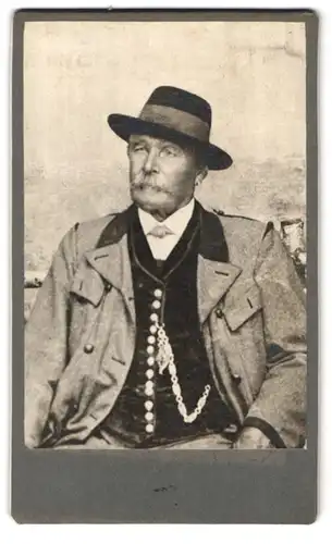 Fotografie unbekannter Fotograf und Ort, Älterer Mann in Sitzposition mit Hut und Taschenuhr
