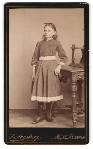 Fotografie F. Augsburg, Berlin-Charlottenburg, Spreestr. 34, Portrait Mädchen mit Schleife im Haar im langen Kleid