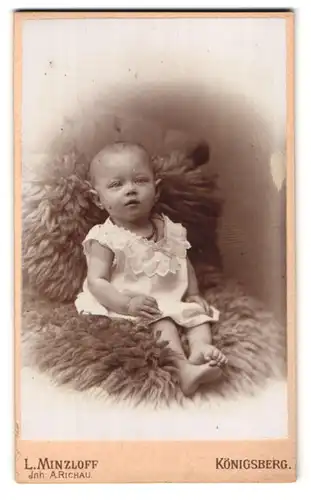 Fotografie L. Minzloff, Königsberg, Theaterstrasse 4, Portrait Baby im Hemdchen auf einem Fell posierend