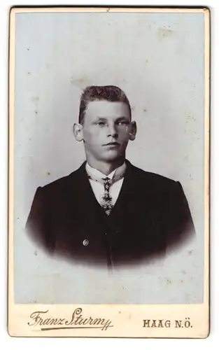 Fotografie Franz Sturm, Haag, Portrait Bursche in schwarzer Jacke mit eleganter Krawatte