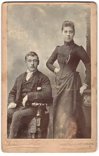 Fotografie Phillips & Co., Nottingham, Marketplace, Dame in dunklem Kleid und sitzender Herr mit Einstecktuch