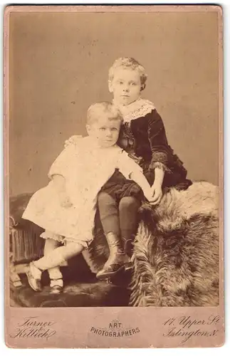 Fotografie Turner & Killick, London-Islington, Upper-Street 17, Zwei Geschwister auf einem mit Fell bedeckten Sofa