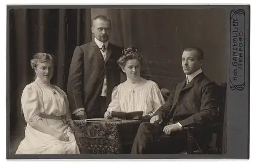 Fotografie Hch. Ganzemüller, Herford, Mönchstr. 4, Herr und Dame mit Brille und junge Frau mit Mann und Buch