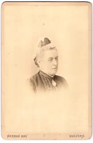 Fotografie Norman May, Malvern, Portrait ältere Dame mit Haube und Kragenbrosche