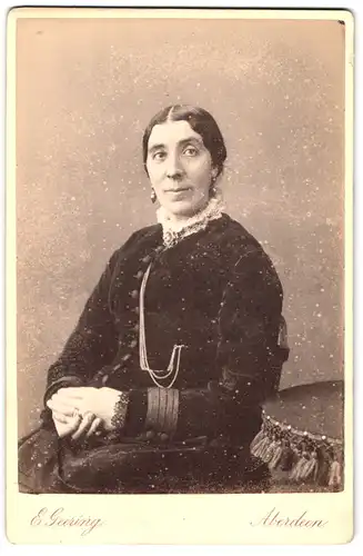 Fotografie E. Geering, Aberdeen, 10, Union Place, Portrait bürgerliche Dame mit Kragenbrosche am Tisch sitzend