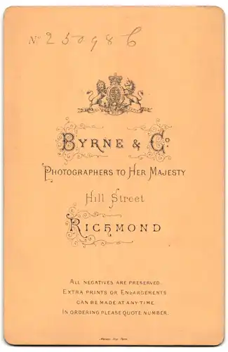 Fotografie Byrne & Co., Richmond, Hill Street, Portrait halbwüchsiger Knabe im Anzug auf Tisch sitzend
