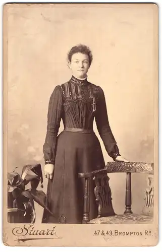 Fotografie W. & J. Stuart, London-SW, 47 & 49, Brompton Road, Portrait junge Dame im Kleid an Stuhl gelehnt