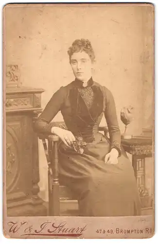Fotografie W. & J. Stuart, London-SW, 47 & 49, Brompton Road, Portrait junge Dame im Kleid am Tisch sitzend